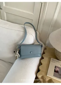 Sofisticata borsa retrò blu sottobraccio esposta in un ambiente minimalista su un divano