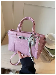 Close-up of pink crinkle textured handbag with silver turn-lock and horse charm