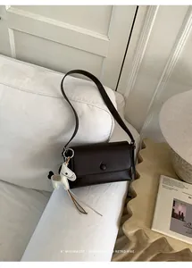 Elegante borsa sottobraccio minimalista marrone scuro con grazioso ciondolo a cavallo