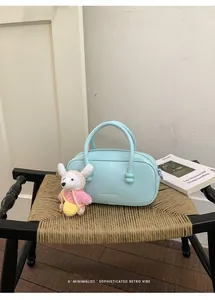 Detailed view of a light blue bowling bag on a woven chair with a cute bear charm.
