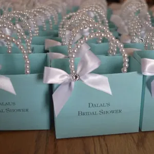 Close-up of turquoise gift bag featuring a pearl handle and white bow