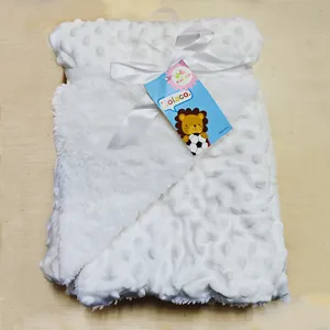 Vue détaillée d'une couverture pour bébé blanche à pois avec ruban et étiquette