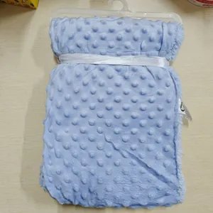 Détail rapproché de la texture douce à pois minky bleu clair sur une couverture bébé pliée