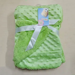 Détail d'une couverture pour bébé pliée vert citron à pois minky et polaire d'agneau avec ruban