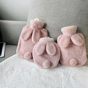 Three pink plush rabbit hot water bottles in different sizes and shapes on a sofa