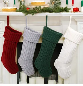 Quattro calze di Natale colorate in maglia appese a un caminetto molto decorato.