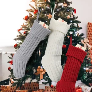 Grandi calze di Natale lavorate a maglia in grigio, bianco e rosso su albero decorato
