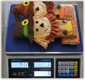 Detail view of two Thanksgiving scarecrow handle covers being weighed on an electronic scale