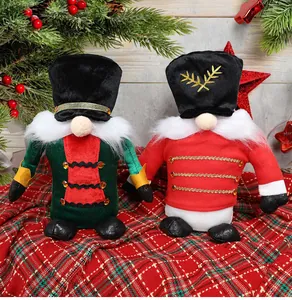 Close-up of two festive plush nutcracker soldier gnomes on a red plaid Christmas cloth