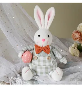 Dettaglio di coniglietto pasquale di peluche bianco con salopette a quadretti verdi