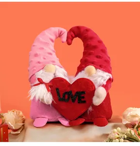 Close-up of pink and red faceless gnome dolls holding a large red heart with LOVE text.