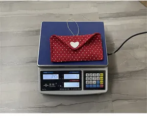 Close-up of a red Valentine fabric heart envelope gift bag weighing 34.5 grams on a scale