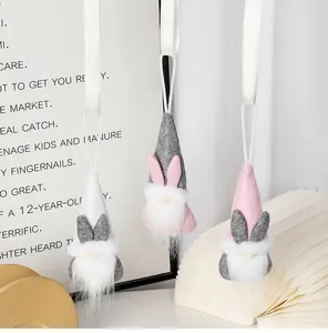 Set de tres gnomos de Pascua de peluche con orejas de conejo colgados sobre fondo moderno