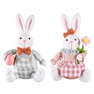 Coppia decorativa di coniglietti di Pasqua in peluche seduti con vestiti a scacchi.