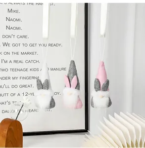 Detalle de tres gnomos de Pascua de peluche colgantes en tonos grises y rosas.