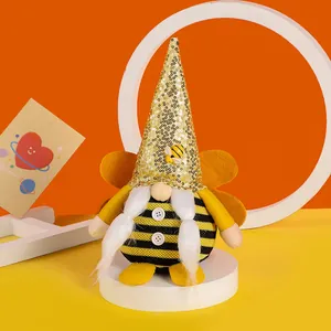 Decorative bee festival plush gnome with golden sequined hat and striped body on white podium.