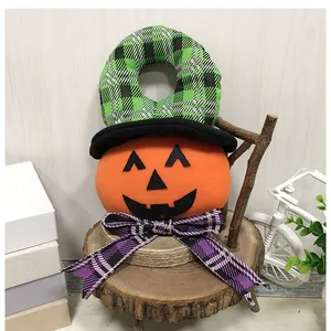 Detailed view of Halloween pumpkin door hanger with green plaid hat and purple bow.