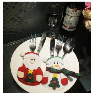 Close-up of festive Santa and Snowman cutlery holders on a white plate with red wine and flowers