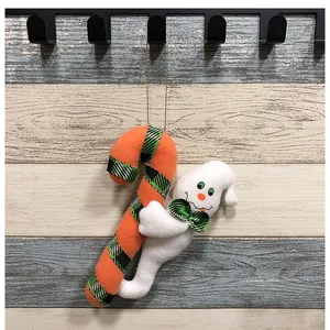 Vista detallada de un fantasma de Halloween de peluche abrazando un bastón de caramelo