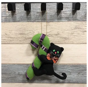 Detalle de adorno colgante de Halloween: gato negro de peluche con bastón de caramelo.