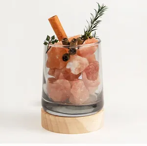 Macro view of pink Himalayan salt stones in a glass diffuser with a wooden base.