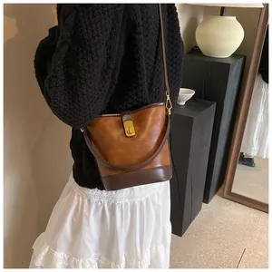 Vintage brown leather bucket bag styled with a black sweater and white ruffled skirt