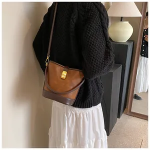 Retro minimalist brown leather bucket bag for women shown worn with a black sweater