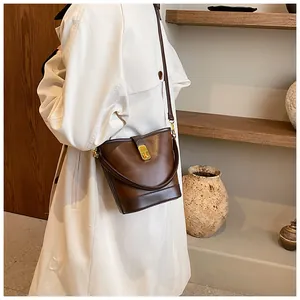 Detailed view of a vintage brown leather bucket bag styled as a shoulder bag on a model.