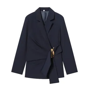 Elegant detail of dark navy blazer featuring draped front and sculptural gold buckle