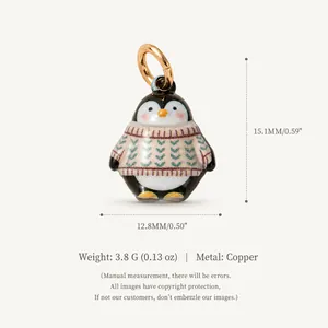 Adorable pendentif pingouin portant un petit pull à motifs en cuivre finition dorée