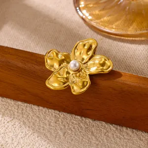 Detailed view of vintage gold flower brooch with hammered metal texture and center pearl