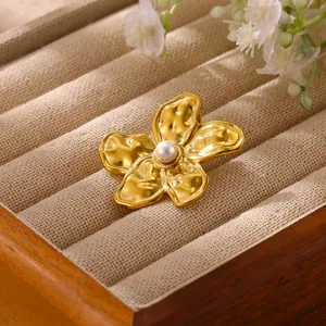Macro detail view of a vintage gold hammered flower brooch with a white pearl center