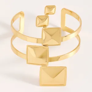 Vue détaillée d'un bracelet manchette doré avec des décorations carrées polies.