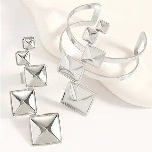 Macro detail of silver geometric pyramid square cuff bracelet and adjustable ring set.