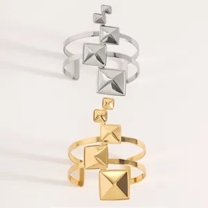 Détail de joncs ouverts or et argent avec clous géométriques en pyramide carrée