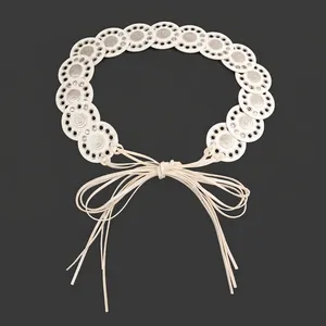 Close-up of bohemian white belt with spliced metal circular disks and knotted strings