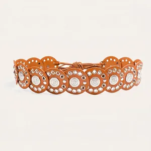 Macro detail of a bohemian tan leather disc belt featuring silver medallion accents