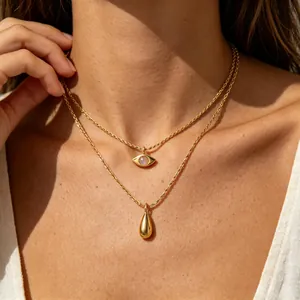 Macro view of double-layered gold necklace with evil eye and teardrop pendants