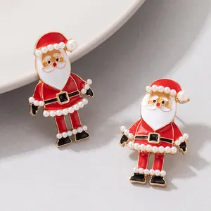 Détail rapproché de boucles d'oreilles Père Noël festives avec perles et émail
