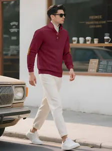 Detail shot of a man wearing a burgundy jacquard knit sweater in an urban street setting.