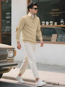 Men's khaki textured knit sweater with stand collar and elbow patches in cafe setting.