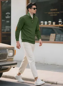 Lifestyle shot showing a man wearing the green jacquard knitted sweater outdoors