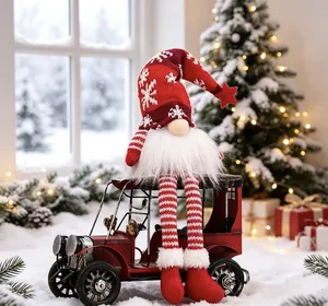 Festive Christmas gnome doll with long legs sitting on a vintage red car model toy