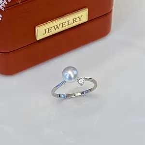 Close-up of a minimalist silver pearl ring with a heart-shaped crystal accent.