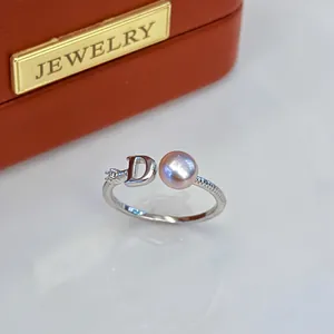 Close-up detail of silver adjustable ring with pink freshwater pearl and letter D