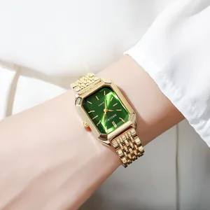 Close-up detail of an elegant square gold watch with a green dial on a woman's wrist