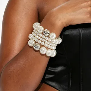 Detailed view of a wide multi-row elastic bracelet with glossy white pearls and silver beads.