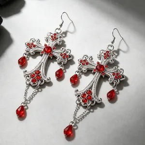 Primo piano di orecchini a croce vintage gotici in argento con strass rossi e pendenti