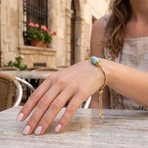 Elegantes verstellbares 18K vergoldetes Armband mit blauer Natursteinperle am Handgelenk.