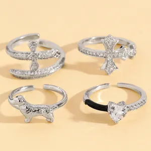 Detailed view of four silver-tone open rings featuring cross, dog, and heart designs.